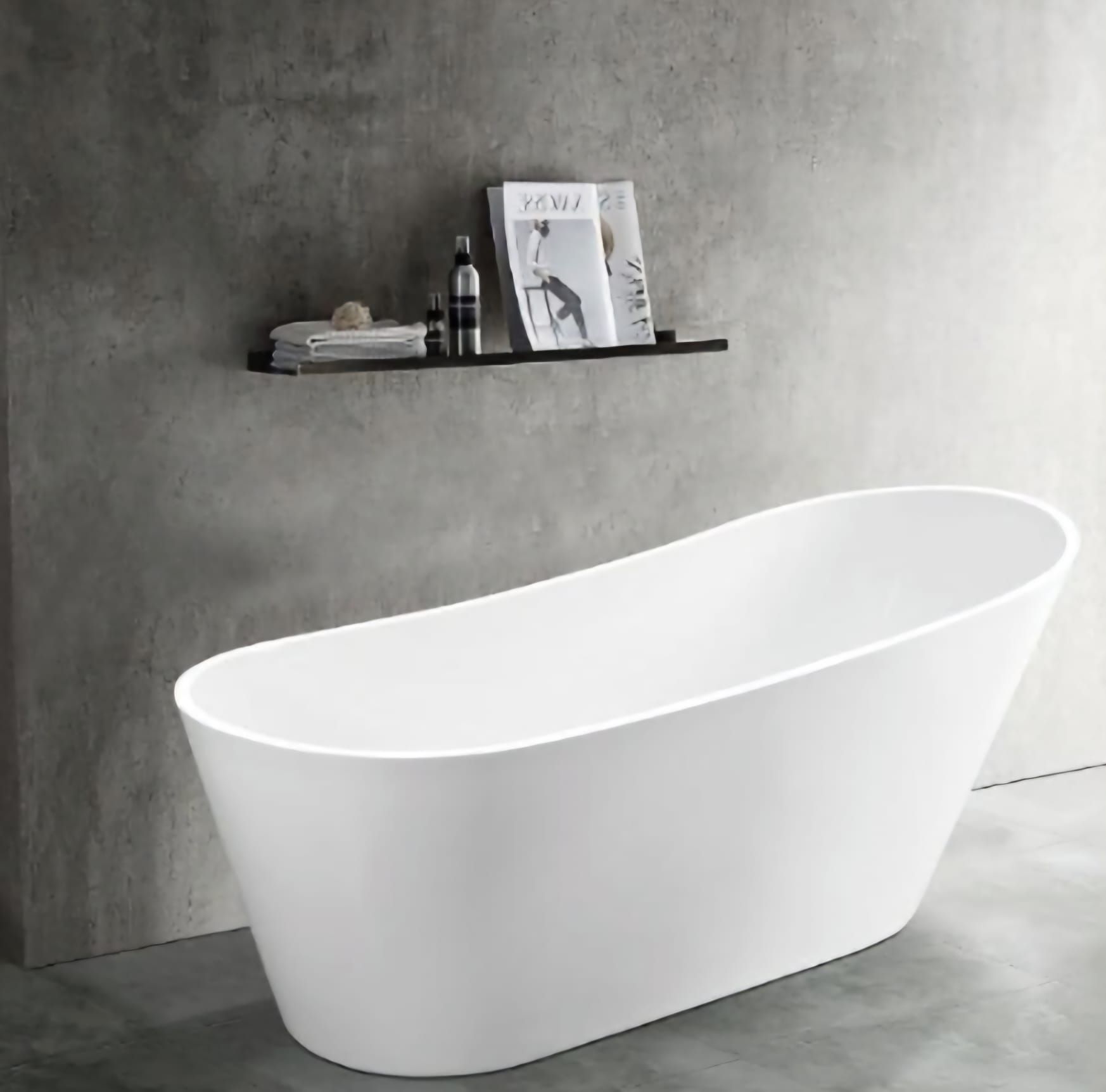 Vasca da bagno bianca indipendente contro una parete grigia con una mensola nera con articoli da toeletta e riviste.