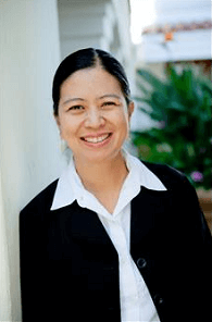 A woman in a black jacket and white shirt is smiling for the camera.