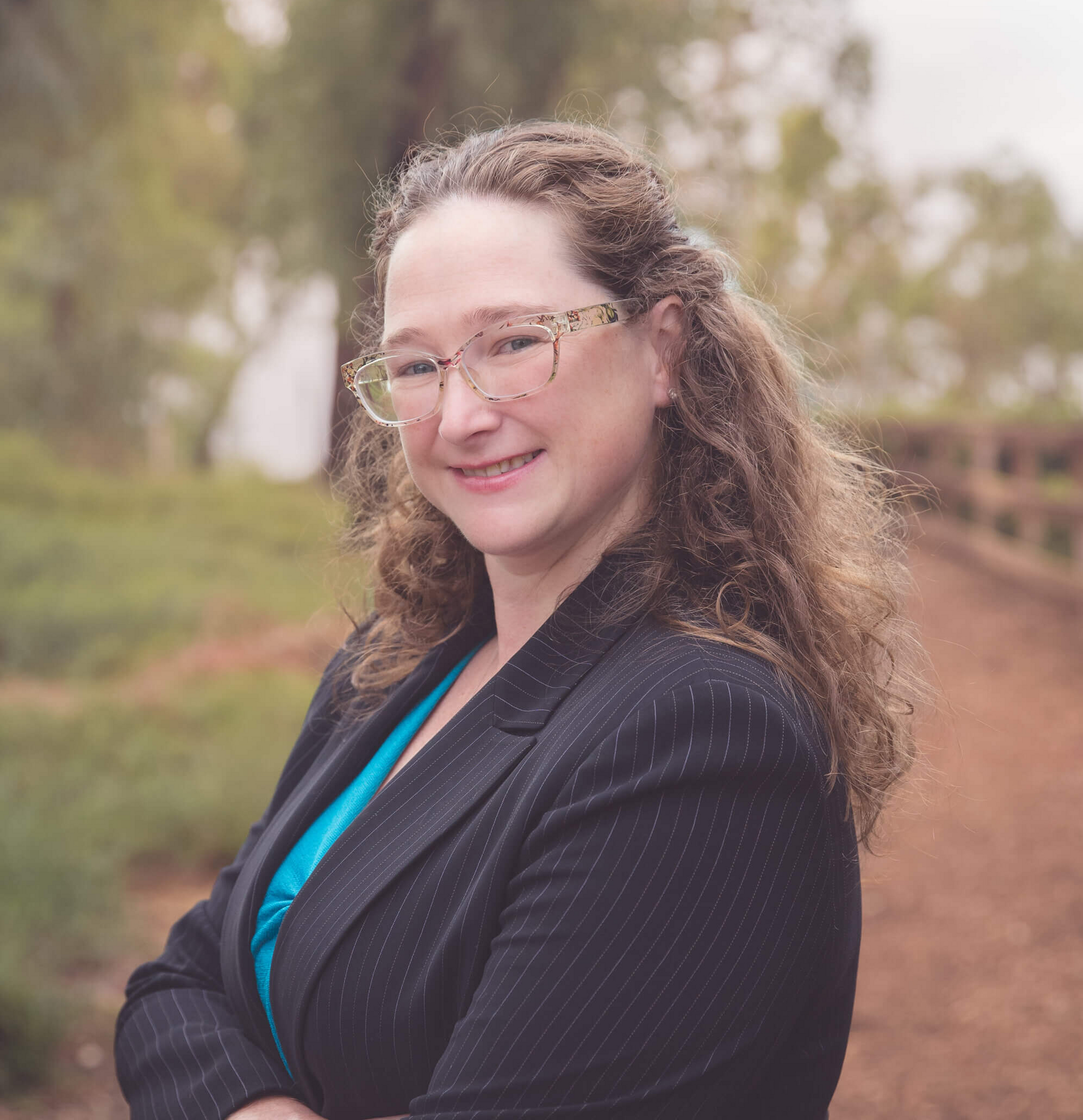 A woman wearing glasses and a black jacket is smiling for the camera.