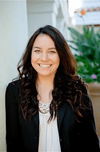 A woman in a black jacket and white shirt is smiling for the camera.