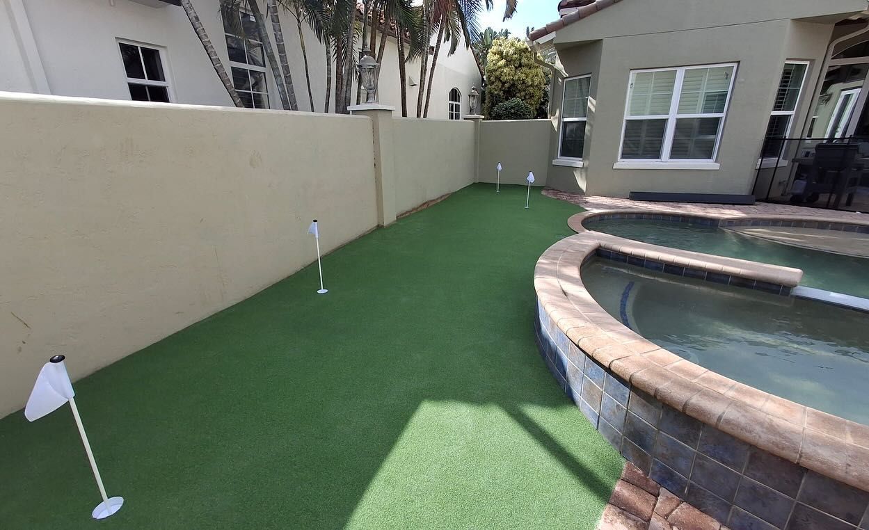 A backyard with a putting green and a pool.