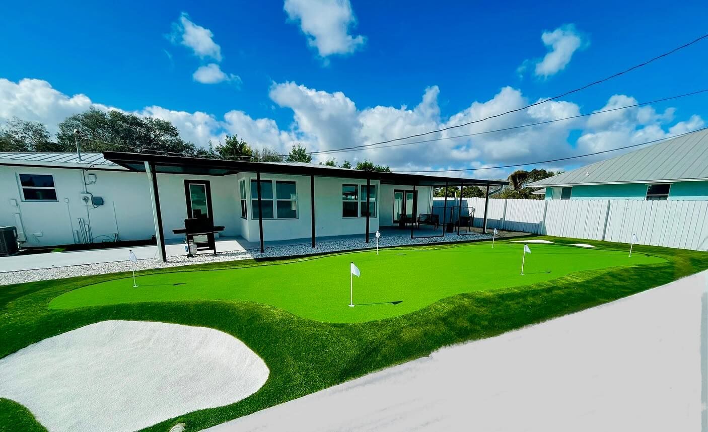 A house with a green putting green in front of it