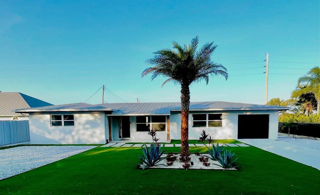 A white house with a palm tree in front of it.