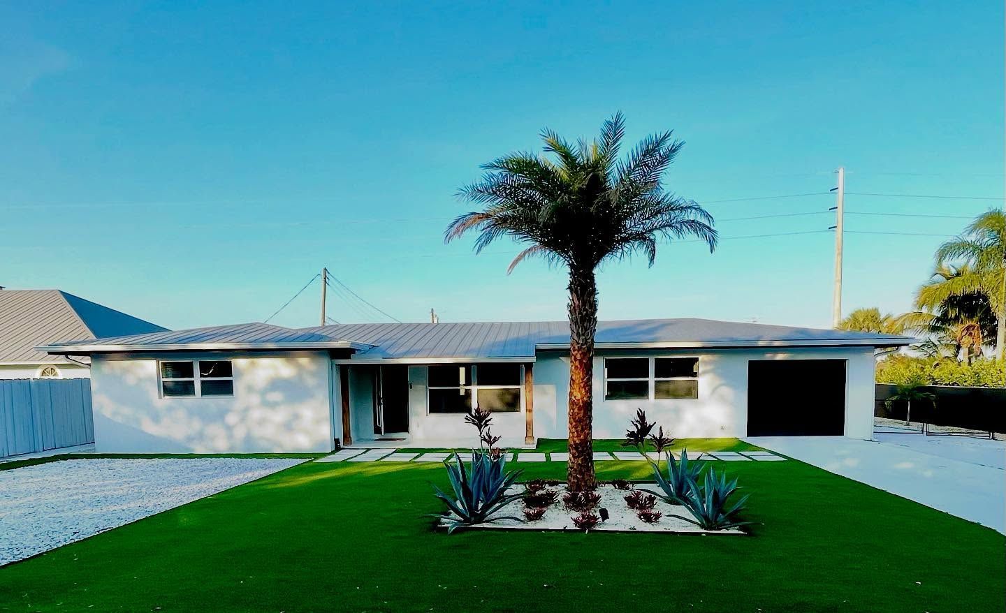 A white house with a palm tree in front of it.