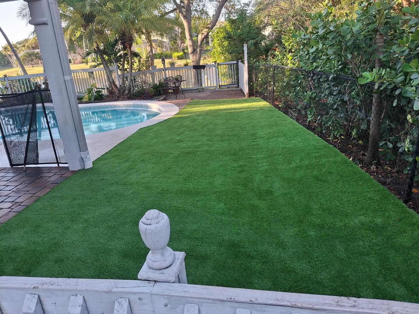 A lush green lawn in a backyard next to a pool.