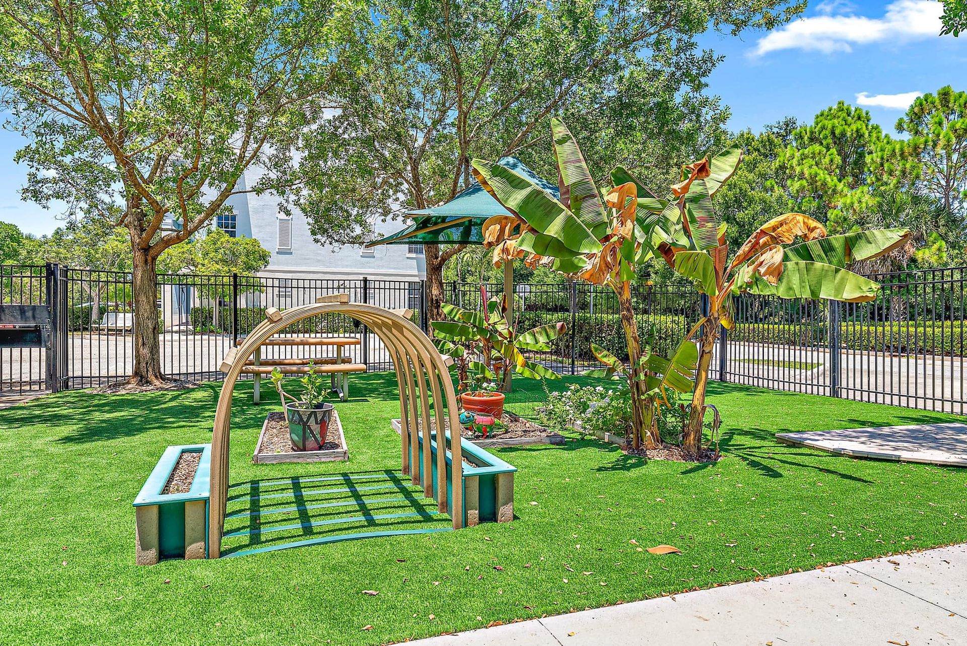 A playground with a bridge , benches , and trees in a park.