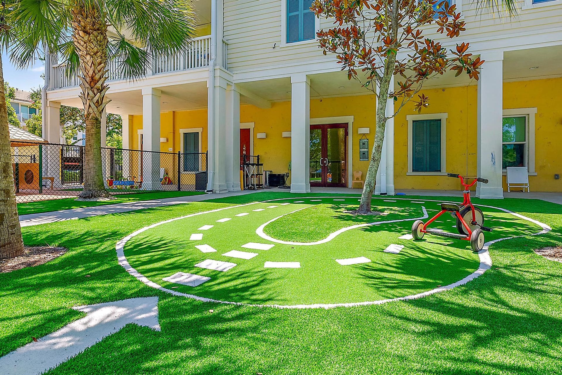 A red bicycle is parked in the grass in front of a yellow house.