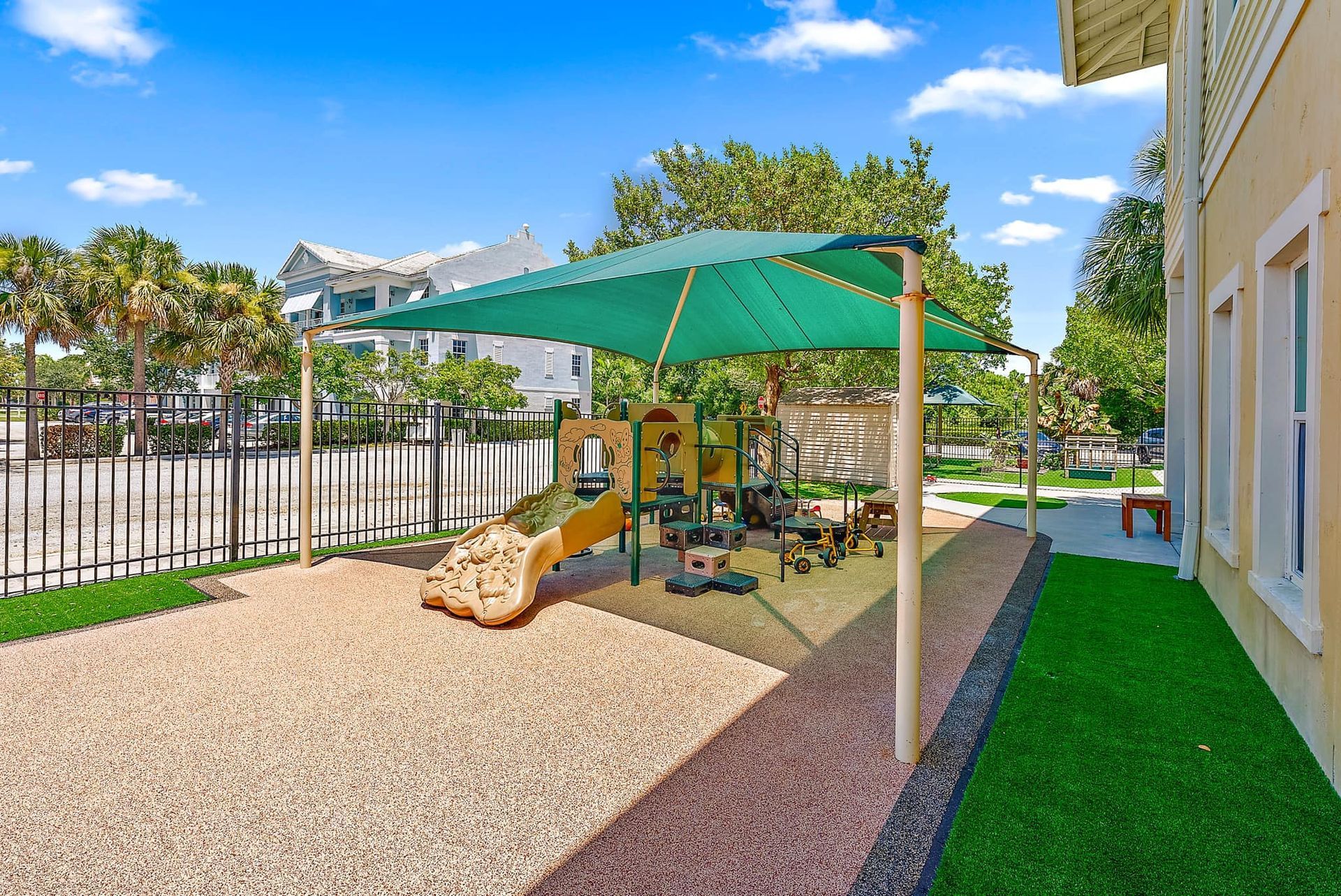 There is a playground with a green umbrella over it.
