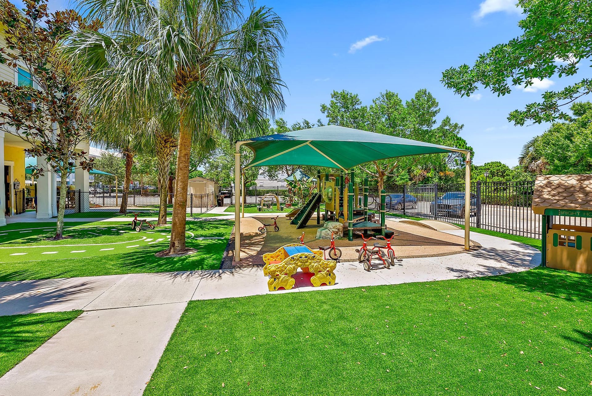 There is a playground with a green umbrella over it.