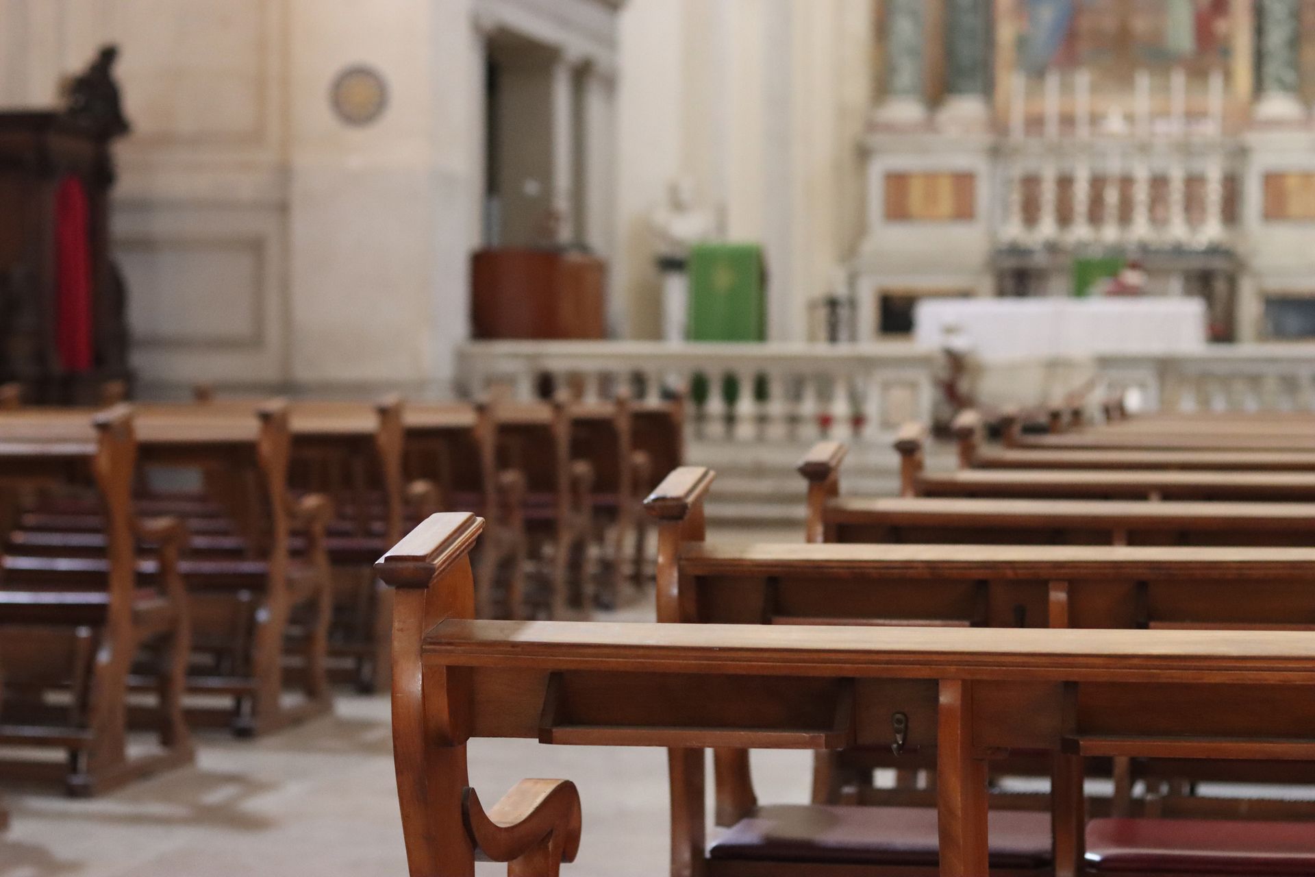 Ci sono file di panche di legno in una chiesa.