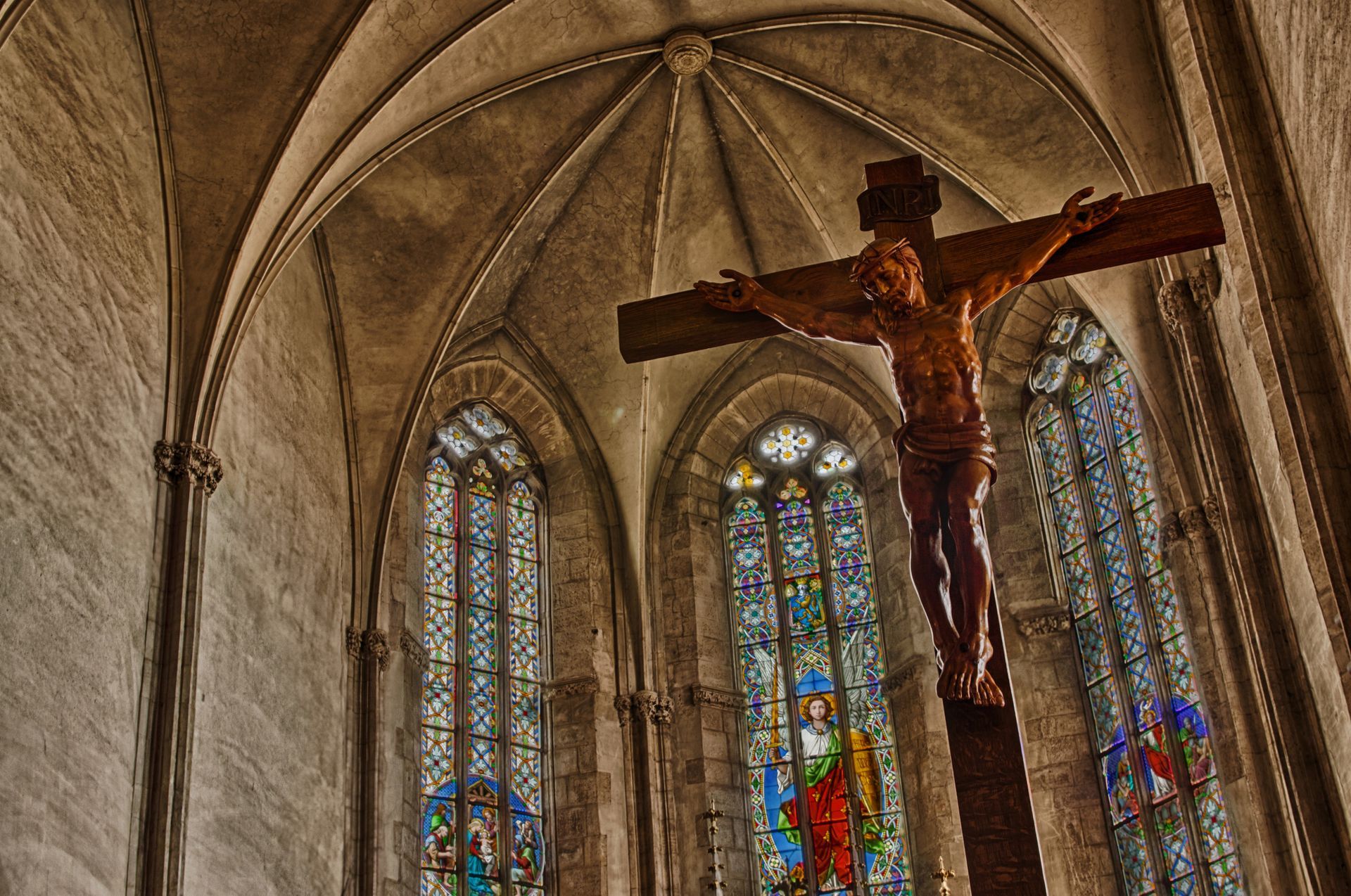 Una statua di Gesù su una croce in una chiesa con vetrate colorate.