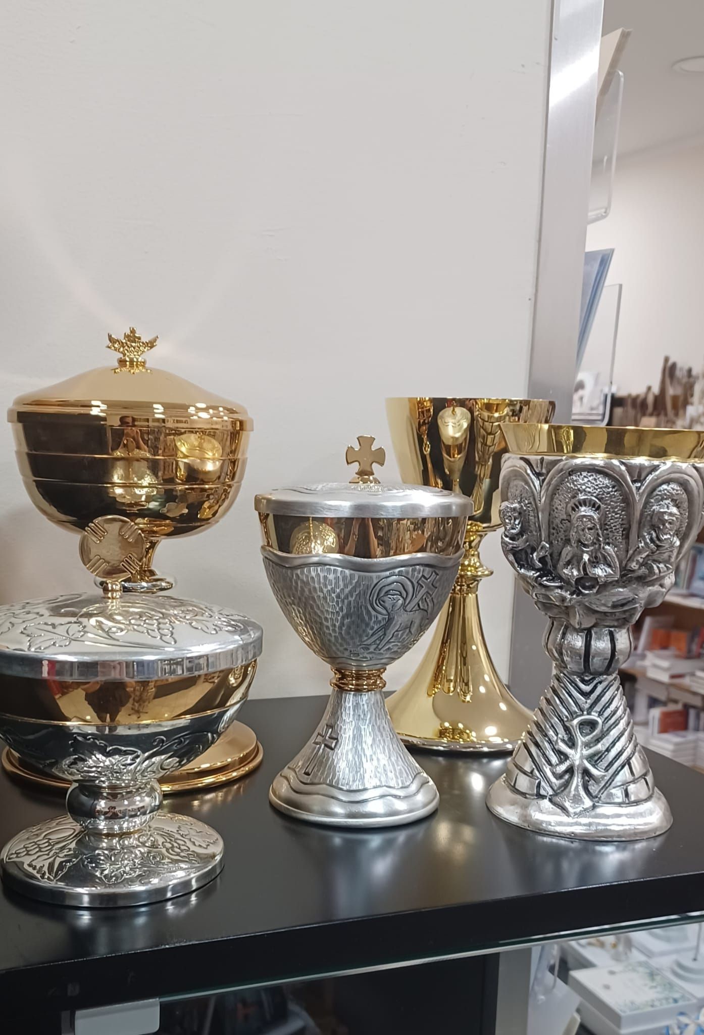 Un gruppo di calici d'oro e d'argento sono appoggiati su un tavolo.