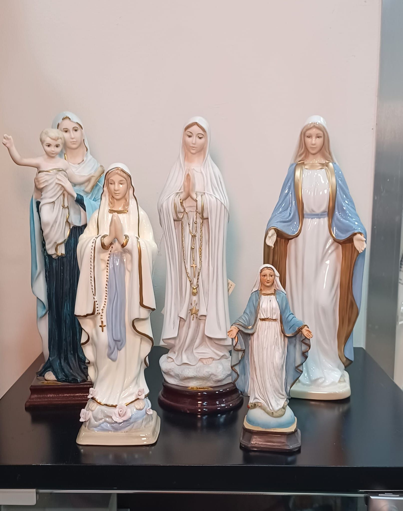 Un gruppo di statue della vergine maria sono sedute su un tavolo.