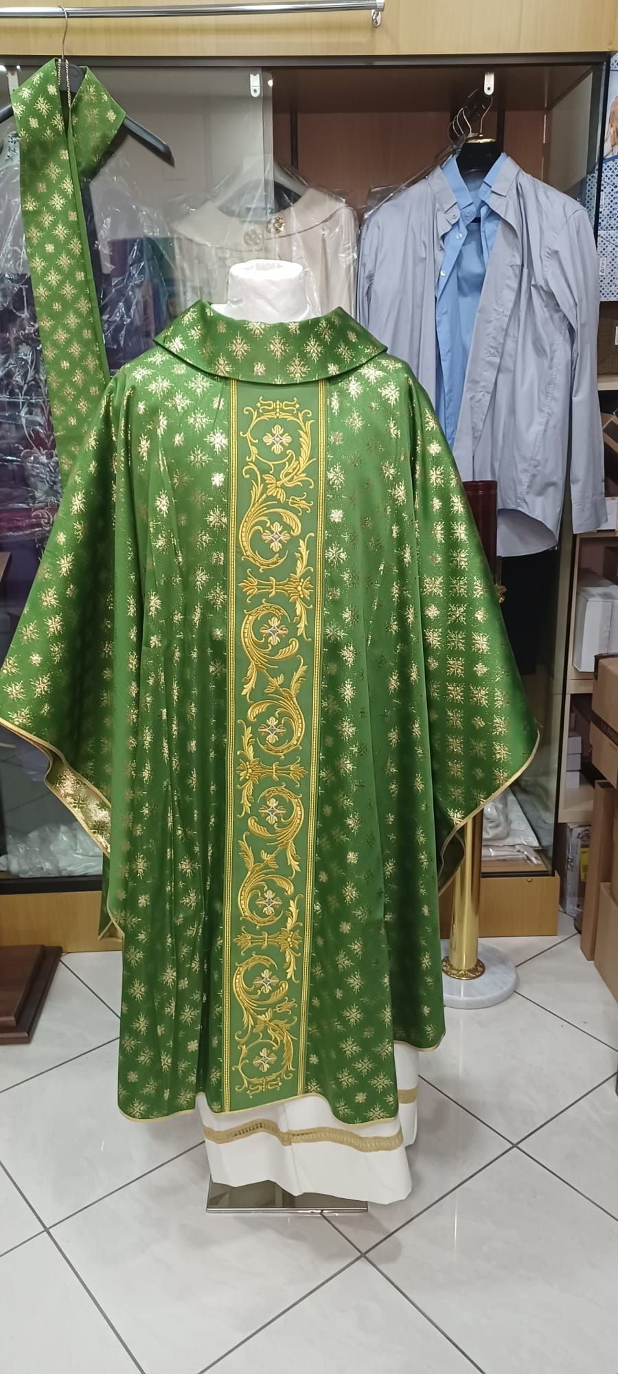 Una pianeta verde e oro è appesa a un manichino in un negozio.