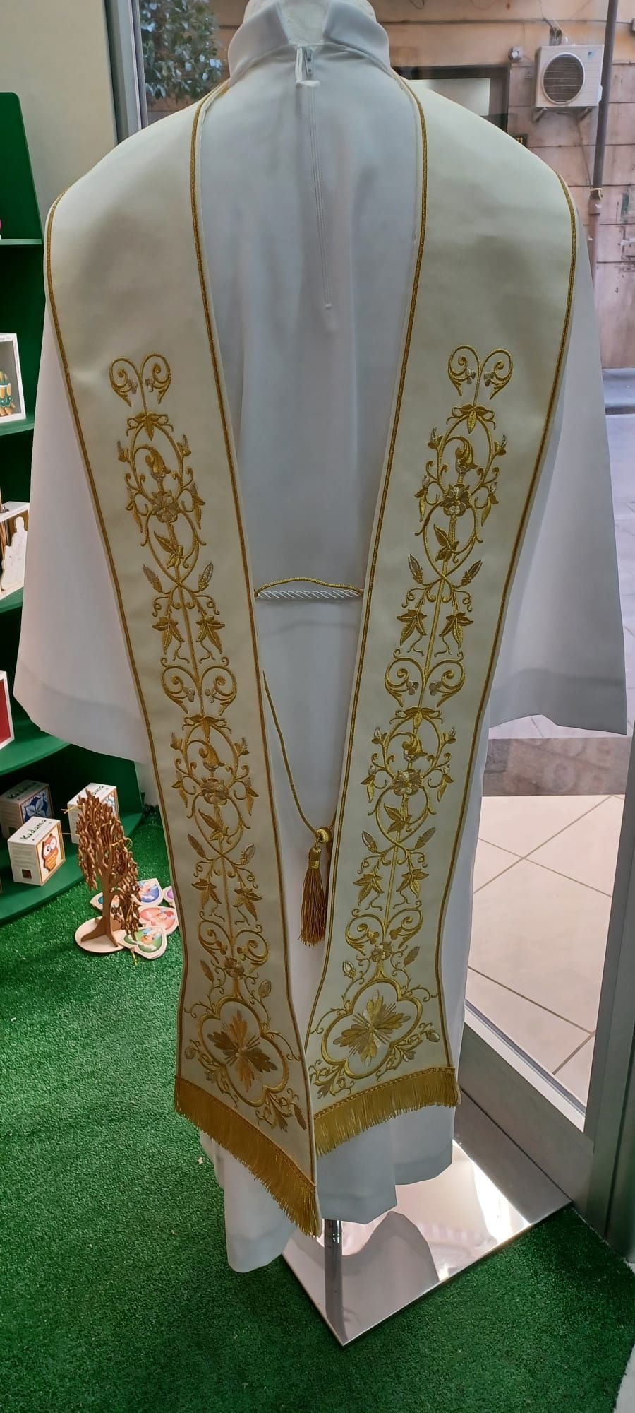 Un gilet bianco con ricami dorati è su un manichino.