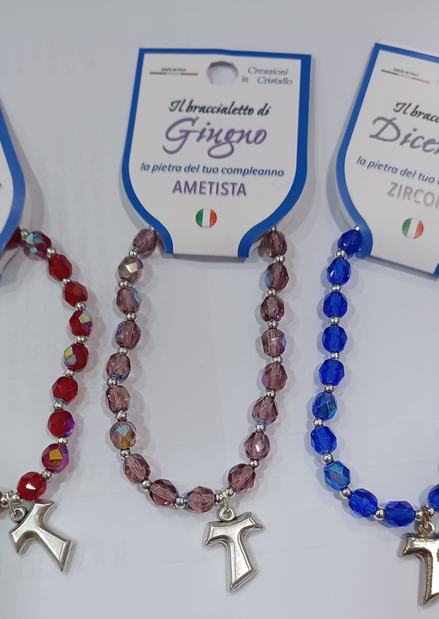 Tre braccialetti di colori diversi con una croce sopra