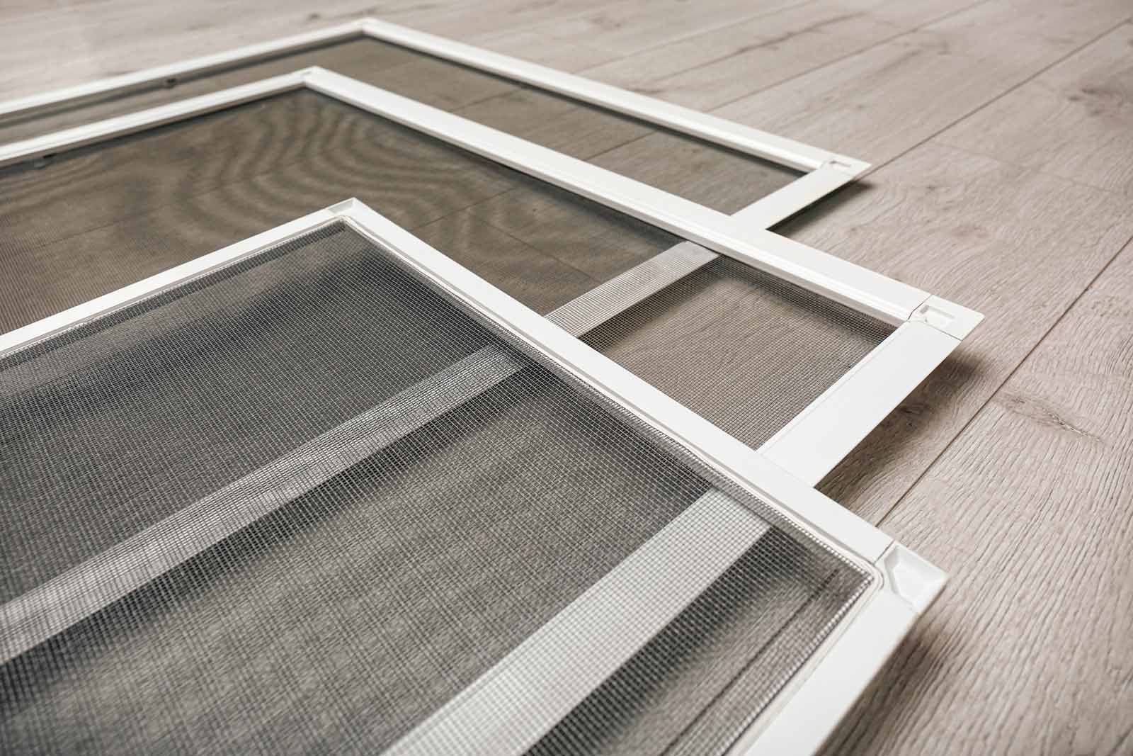 Three mosquito screens are stacked on top of each other on a wooden floor.