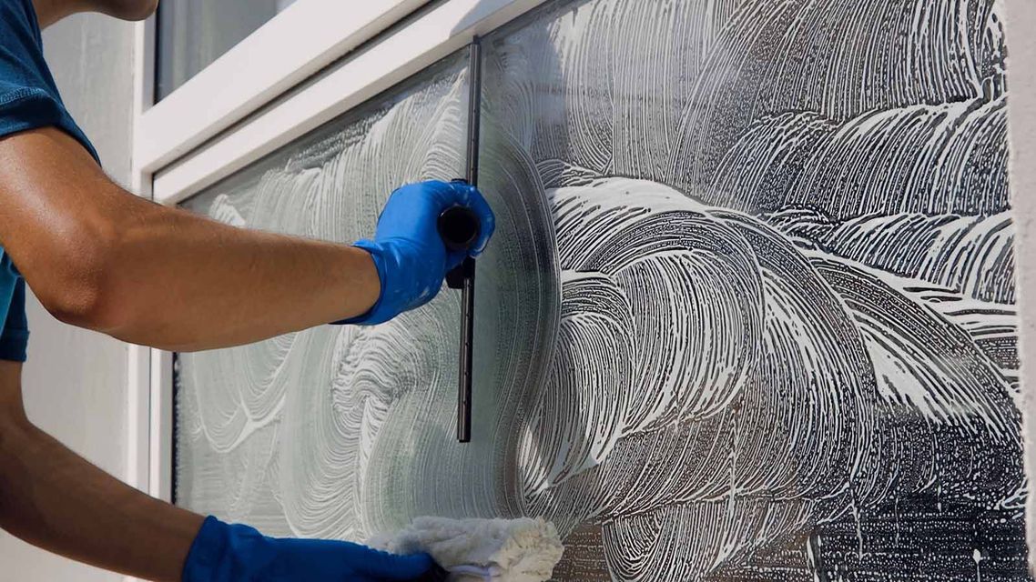 A man is cleaning a window with a squeegee.