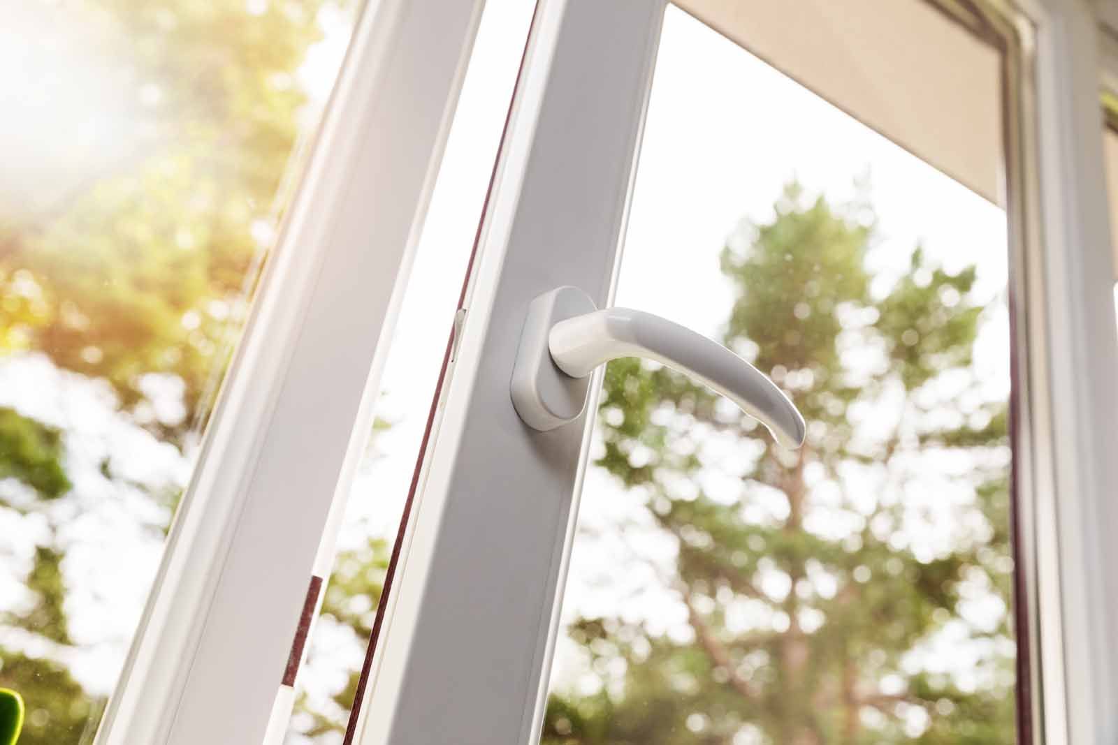 A close up of an open window with trees in the background.