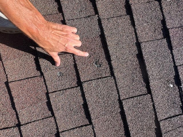 A person is pointing at a hole in a roof.