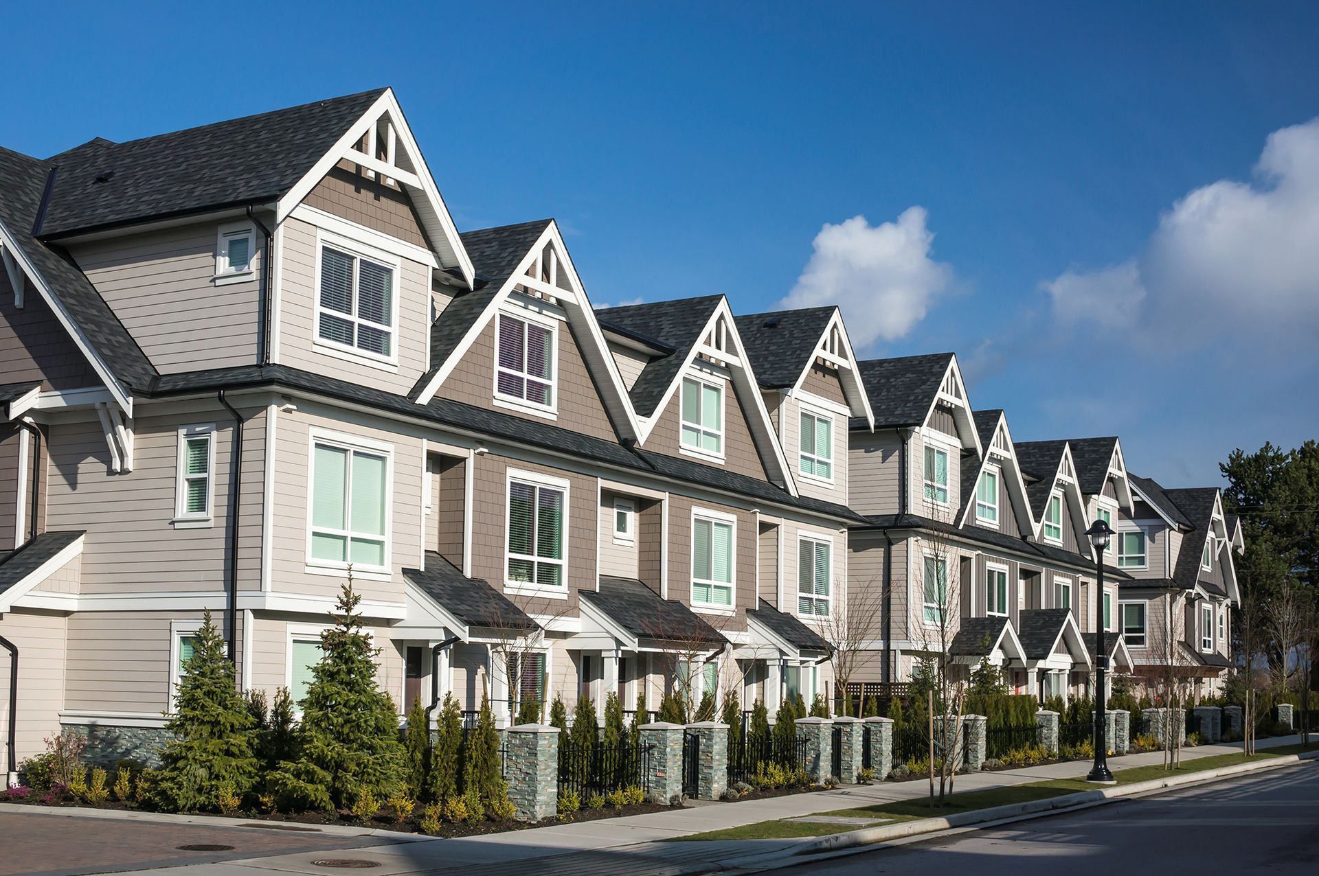 A row of houses on a sunny day with a blue sky in the background.