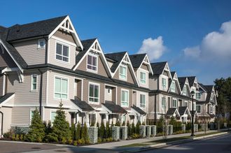 A row of houses on a sunny day with a blue sky in the background.