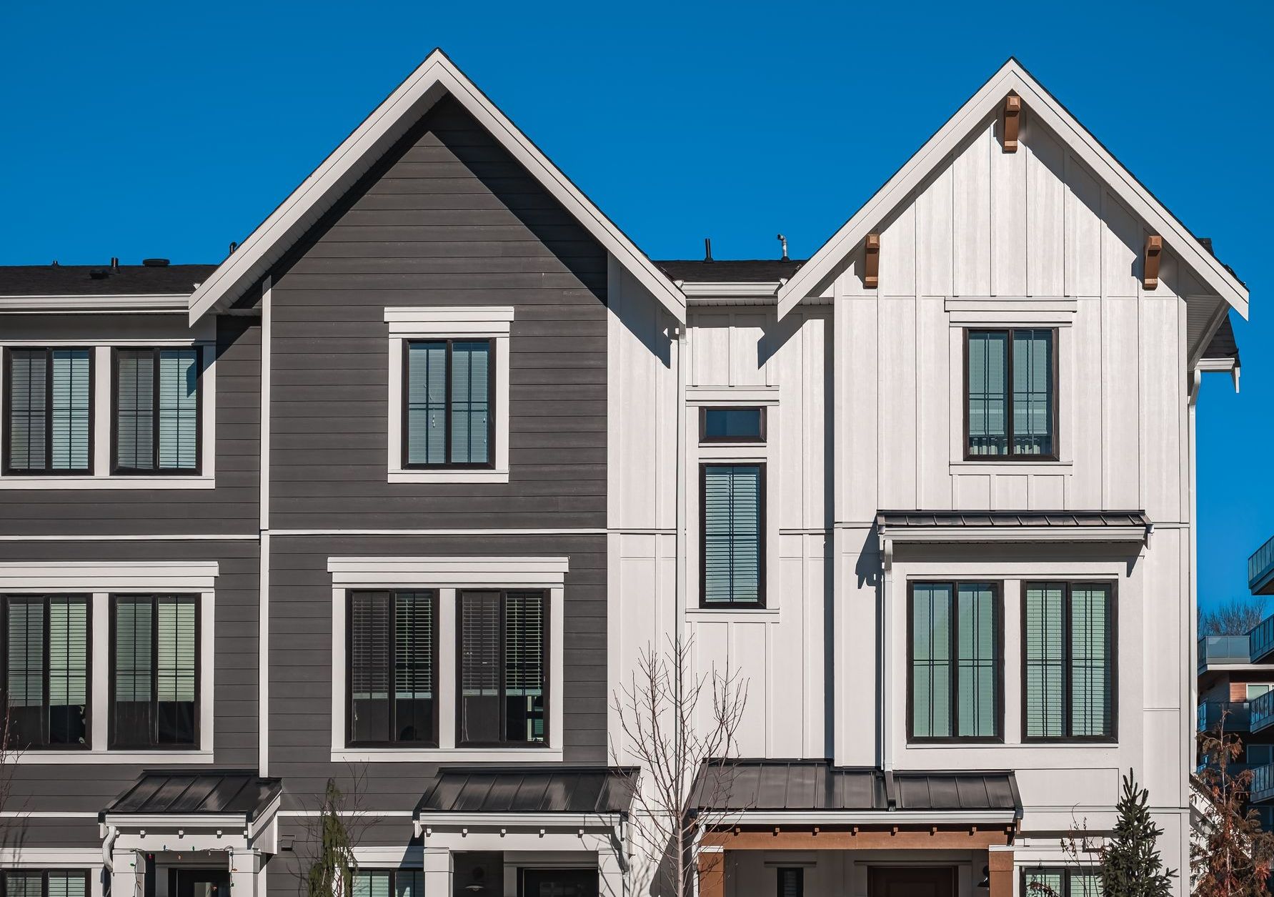 A row of houses with black windows and a blue sky in the background.