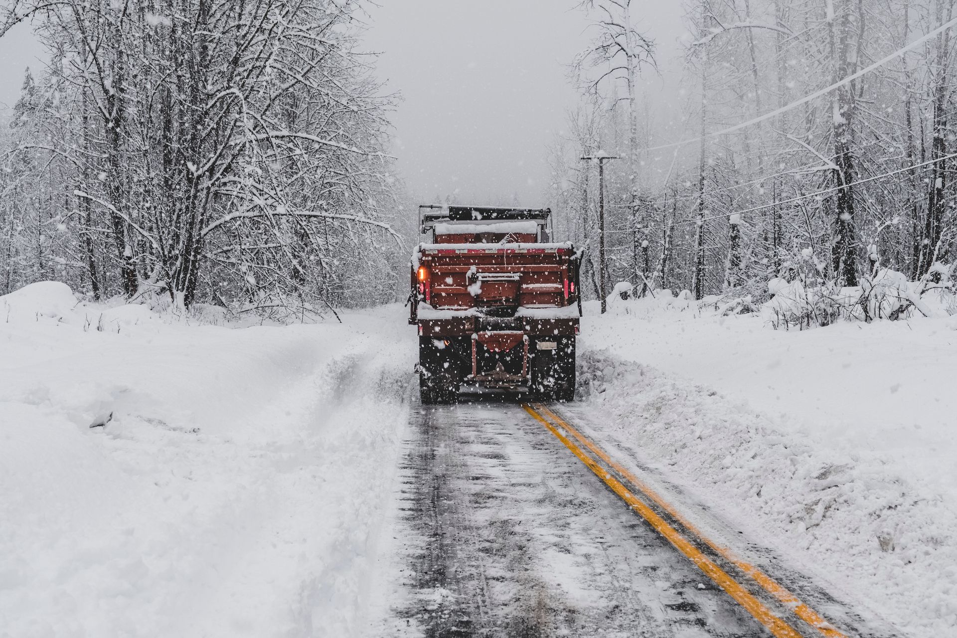 A truck is driving down a snow covered road.