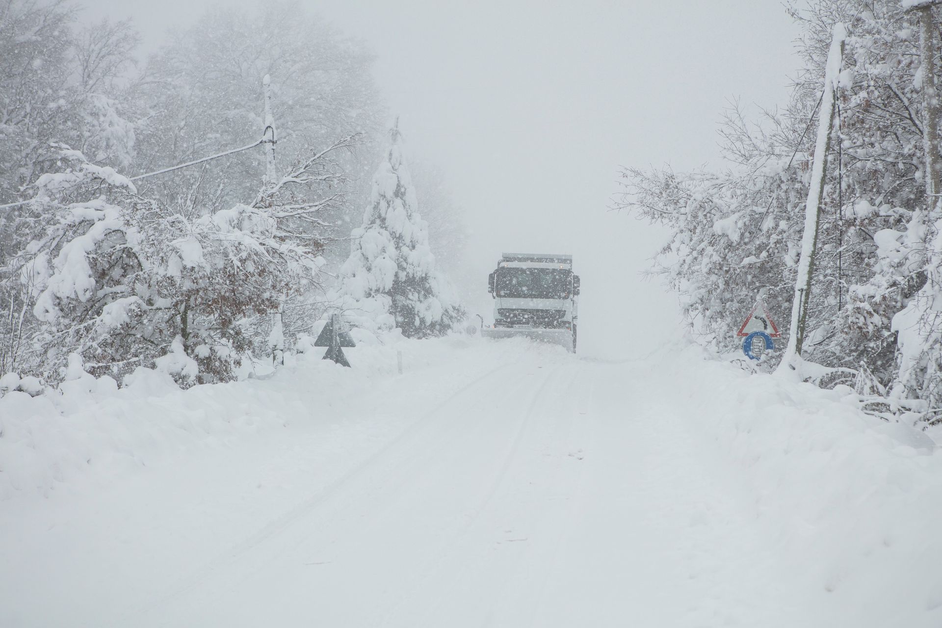 A car is driving down a snow covered road.