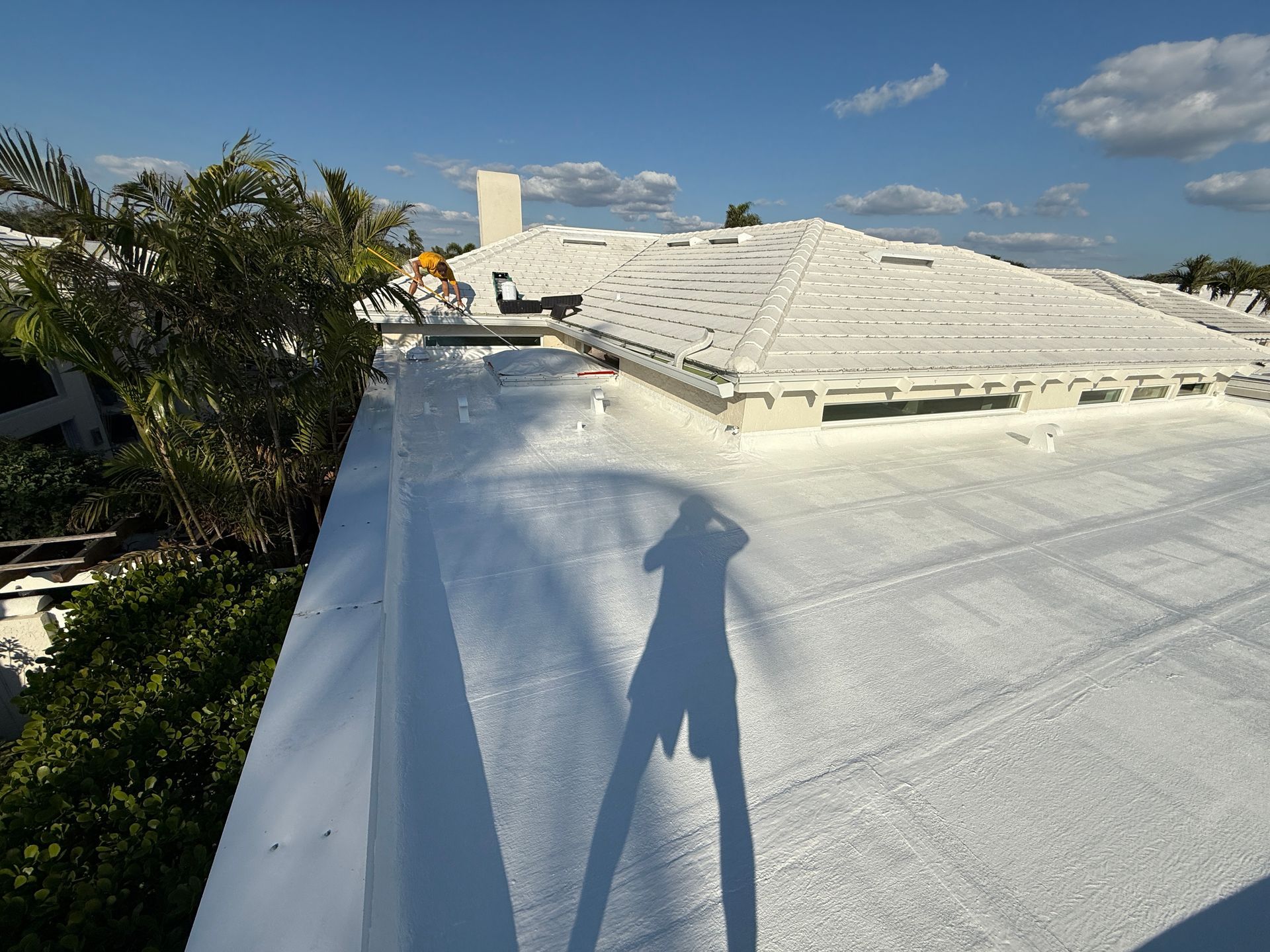 White roof of a building with a blue sky. A shadow is cast onto the roof.