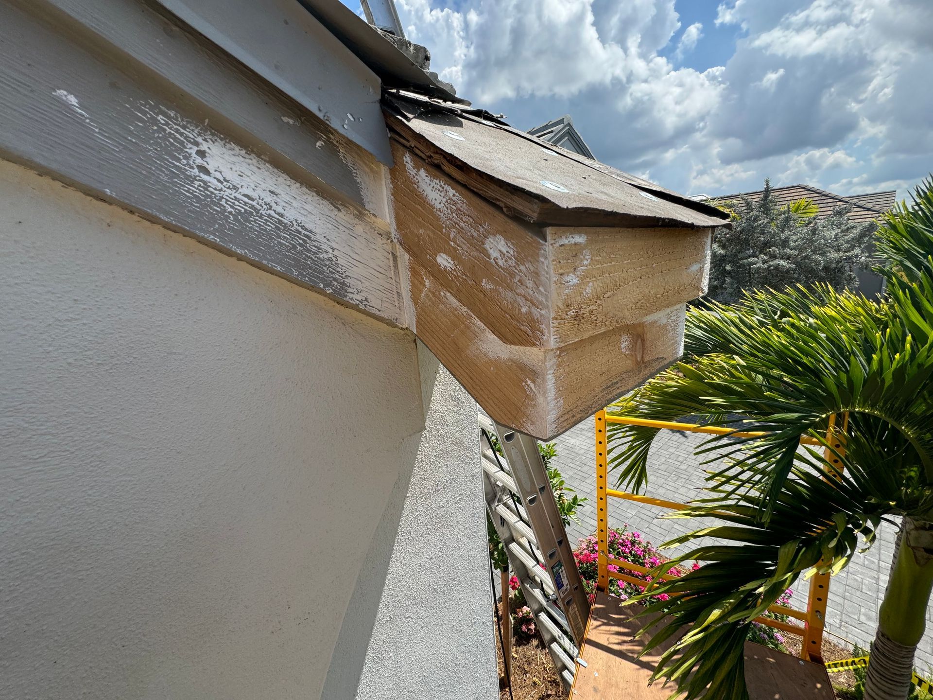 A weathered, angled wooden box attached to a building's gray siding under a cloudy sky.