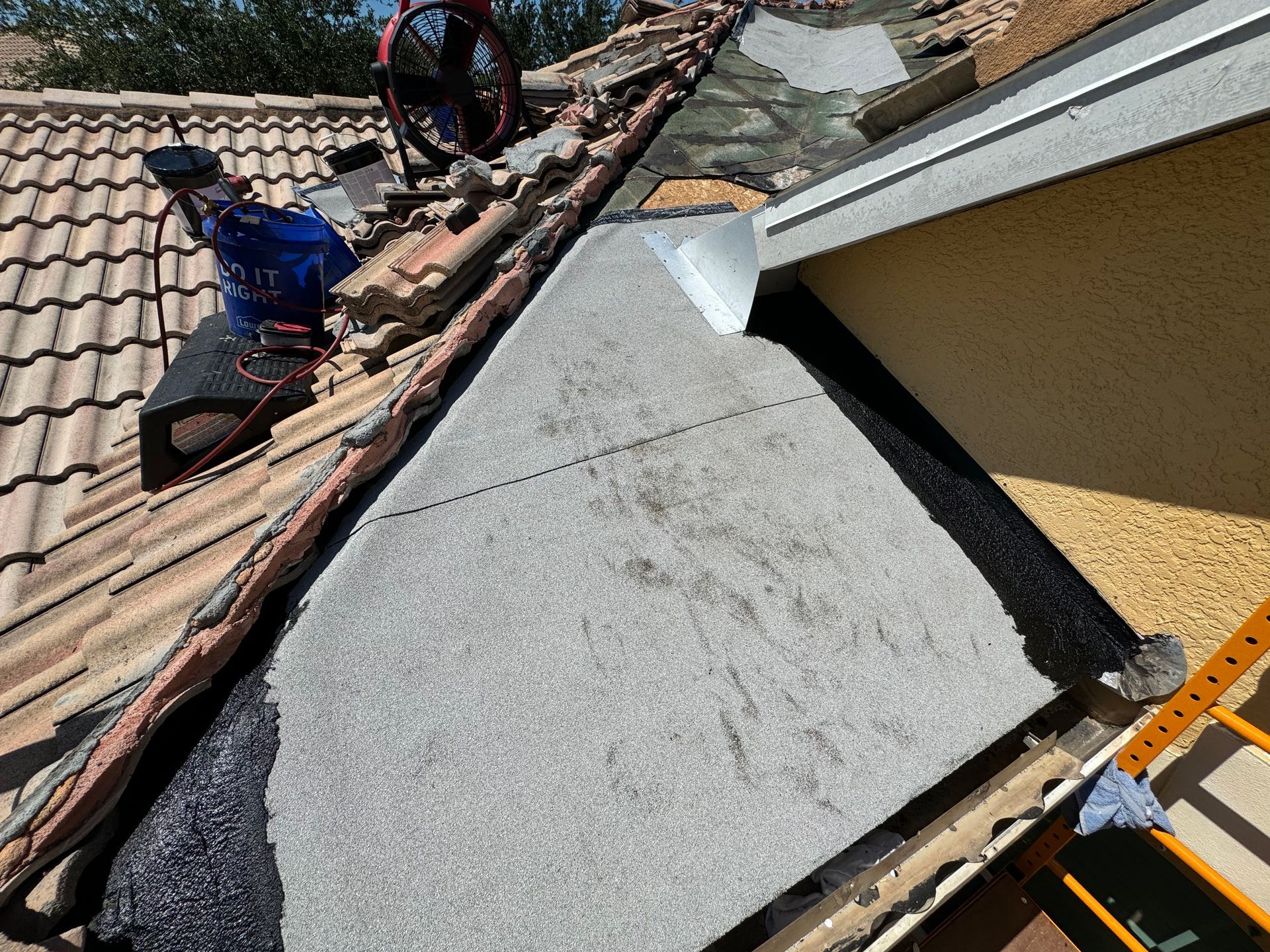 Roof partially covered with tiles, showing underlayment; construction in progress.