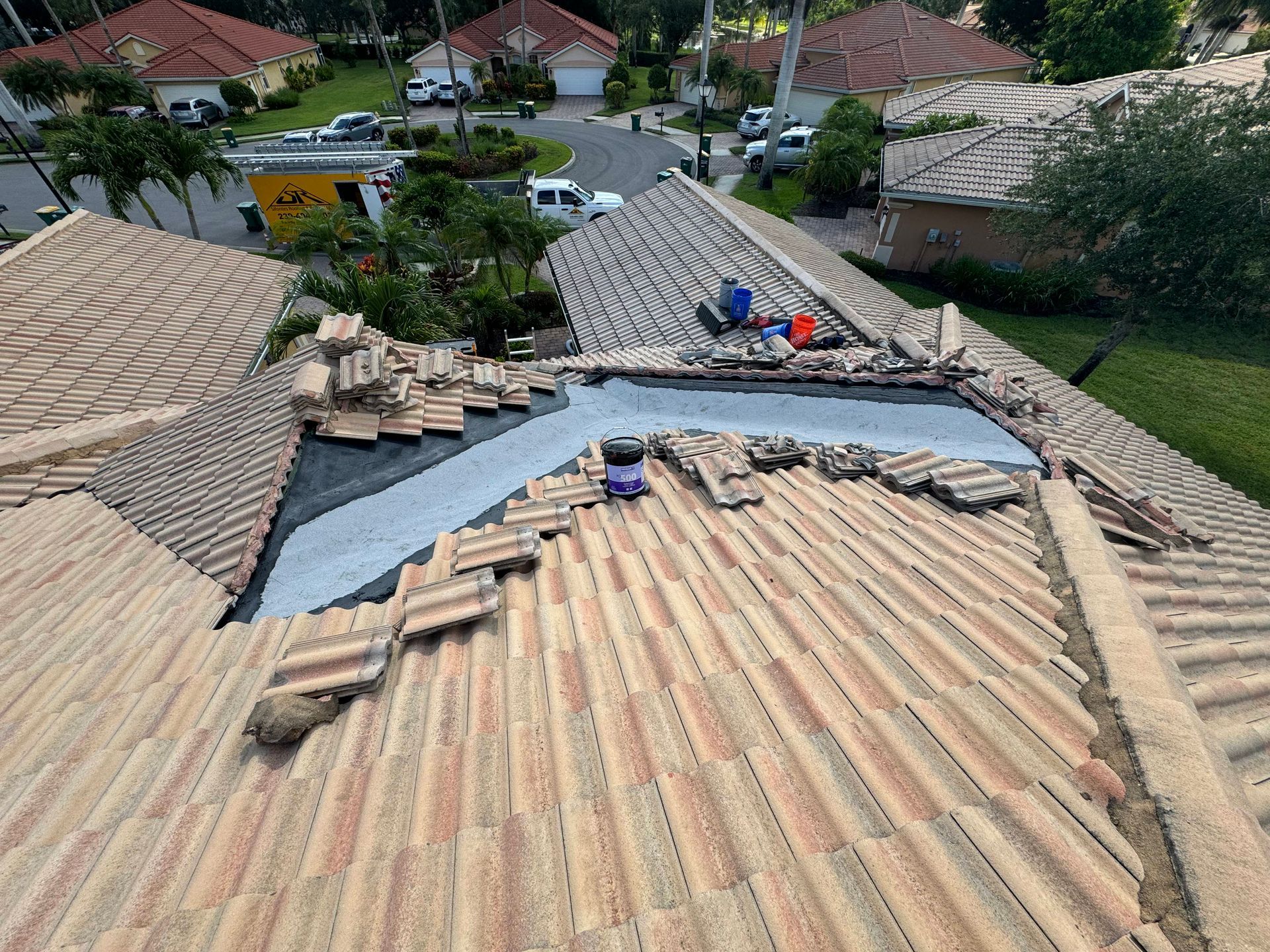 Roof partially disassembled for repair. Workers on a tiled roof, removing tiles.