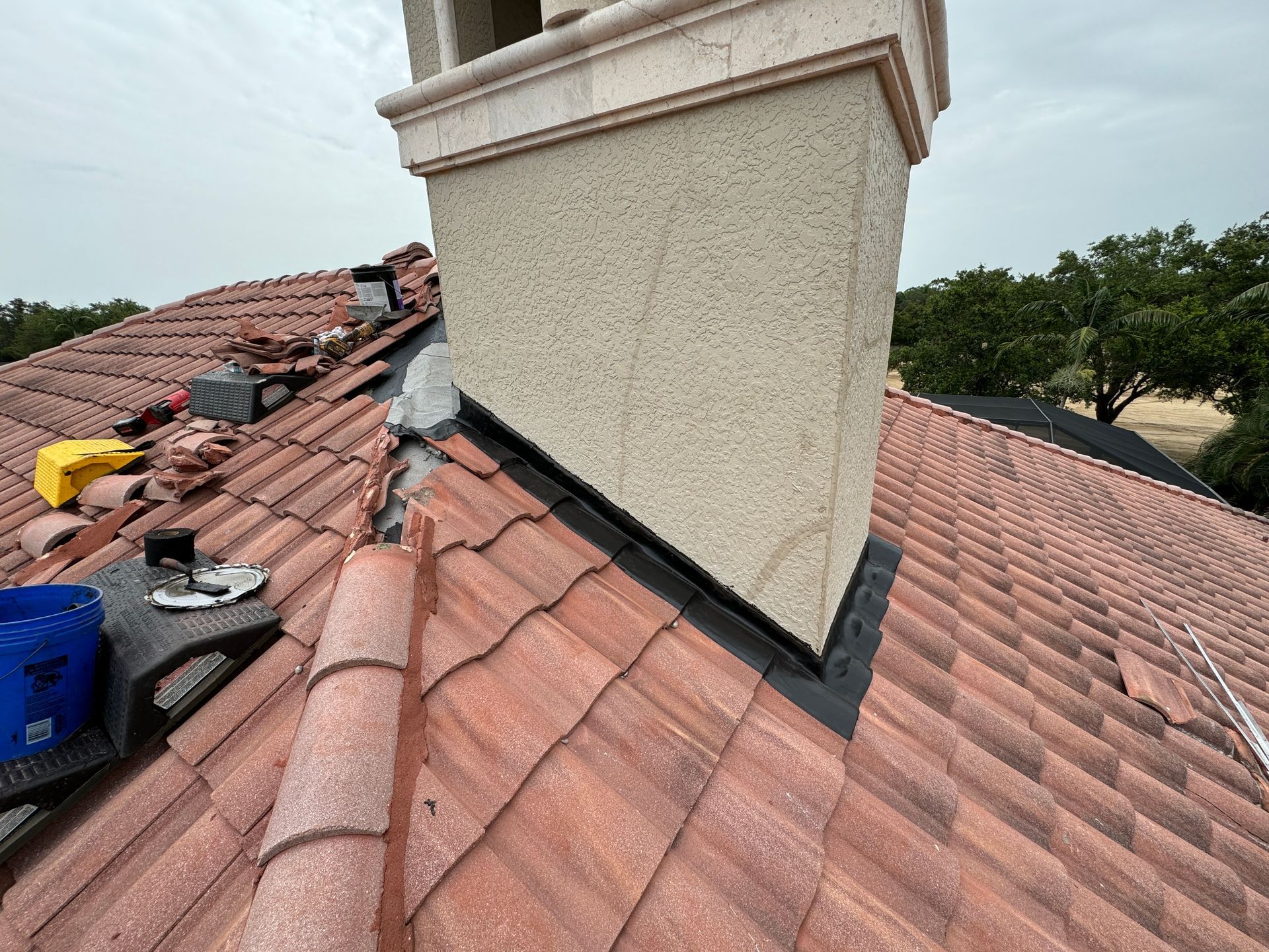 Clay tile roof with chimney and flashing.