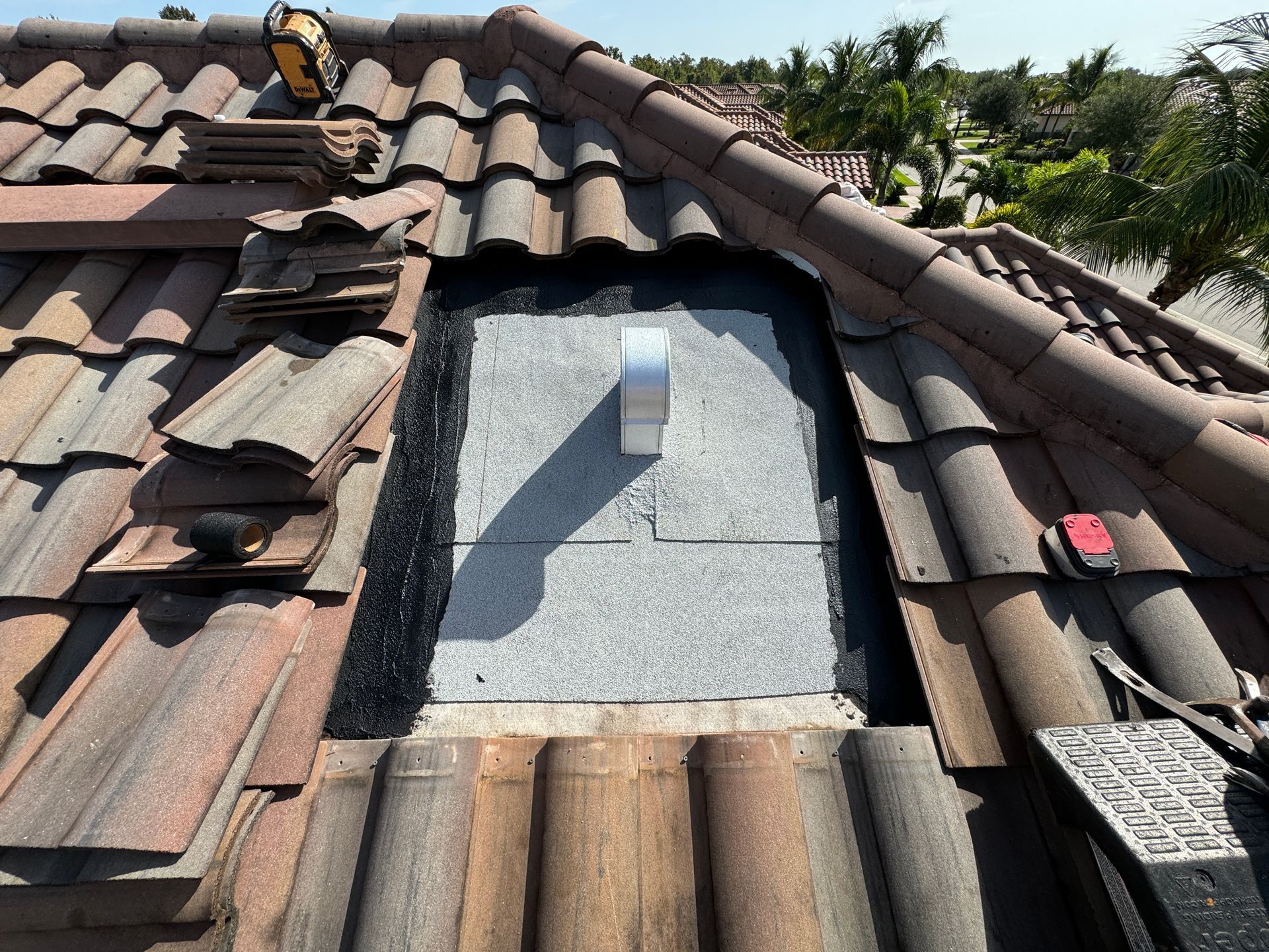 Roof repair with missing tiles, exposing underlayment around a vent pipe.