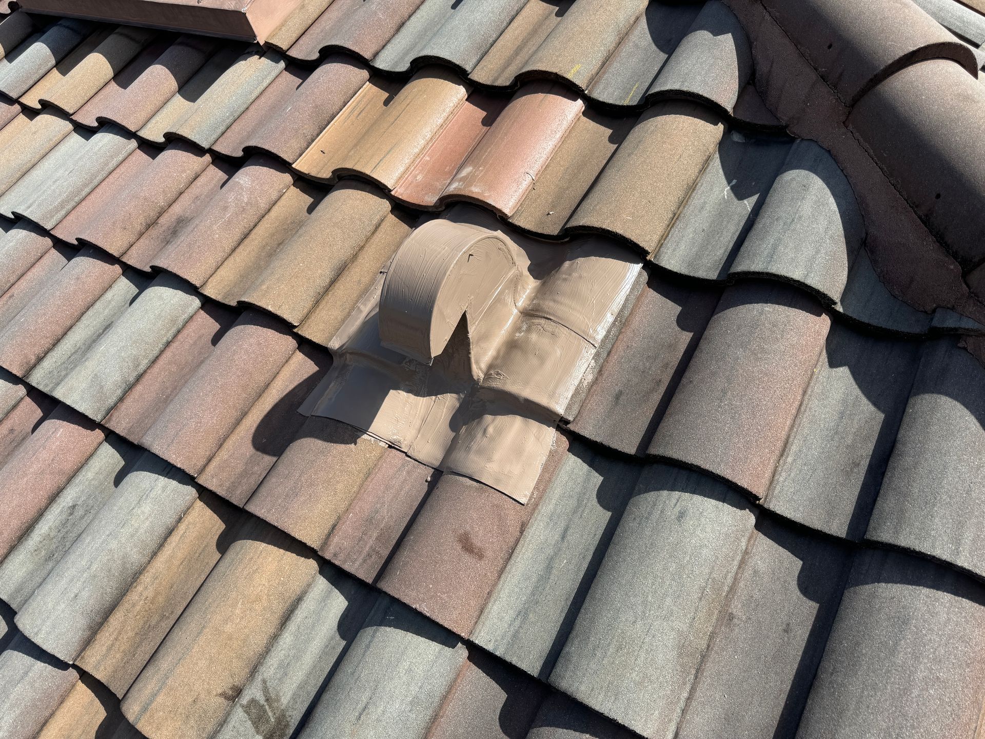 Close-up of a damaged terracotta tile roof with broken and missing tiles, showing weather wear.