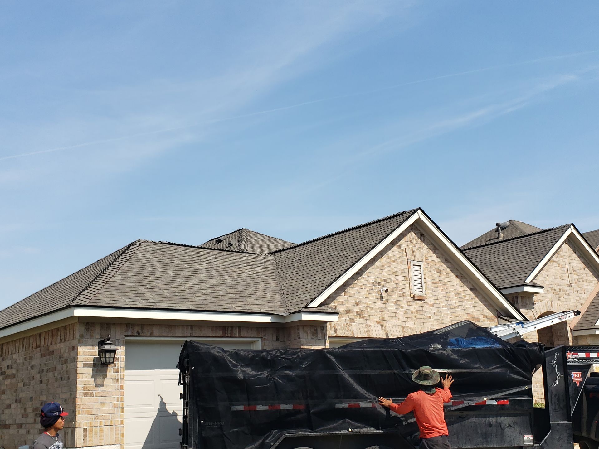 A worker wearing gloves is installing siding on the exterior of a house.