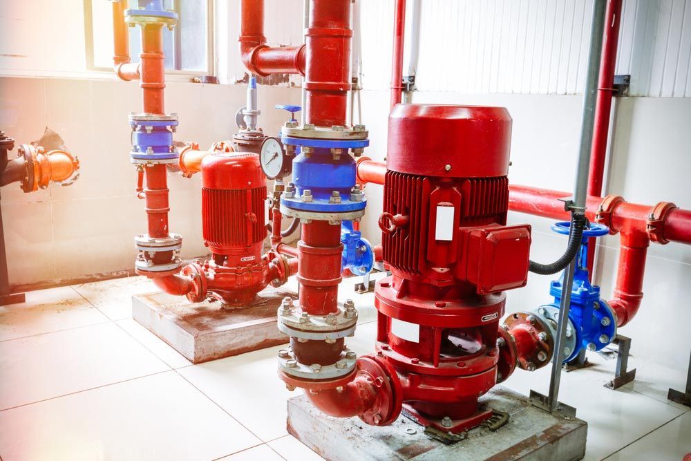 Red Pump System With Blue and Red Pipes in a White-tiled Room — Keyeng in Slade Point, QLD