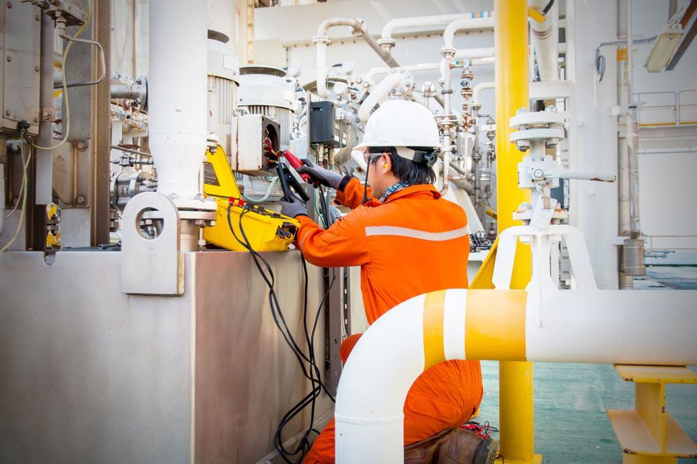 Worker in Orange Coveralls and a White Helmet Working on Industrial Equipment — Keyeng in Slade Point, QLD