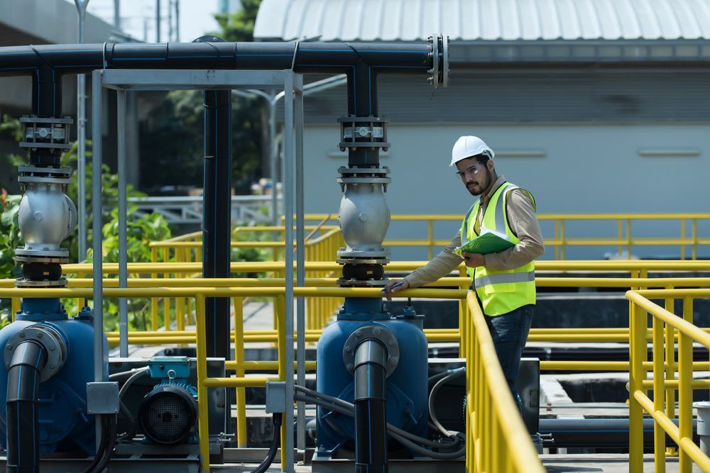 Man in Hard Hat and Vest Inspecting Machinery at a Water Treatment Plant — Keyeng in Slade Point, QLD