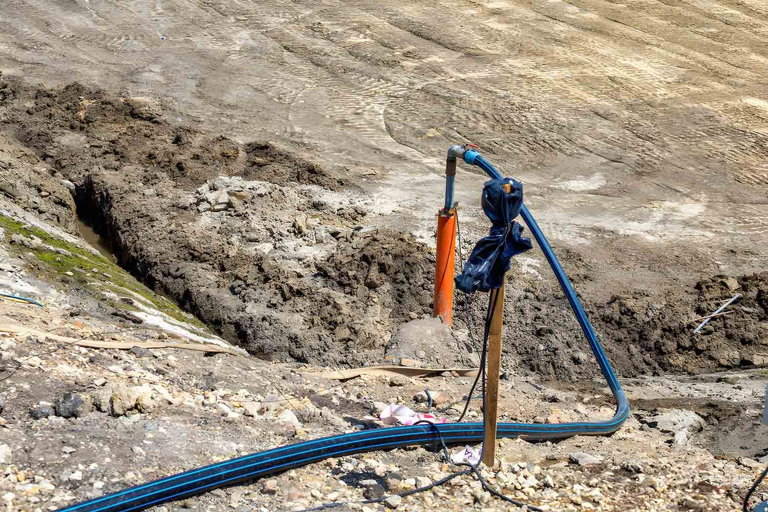 Hose and Pump in a Muddy, Barren Landscape, Possibly a Construction or Mining Site — Keyeng in Slade Point, QLD