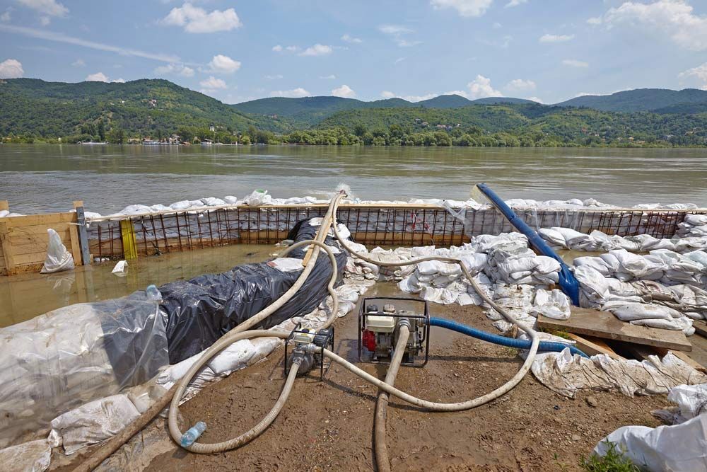 Sandbags and Pumps Used to Control Flooding Along a River, With Hills in the Background — Keyeng in Slade Point, QLD
