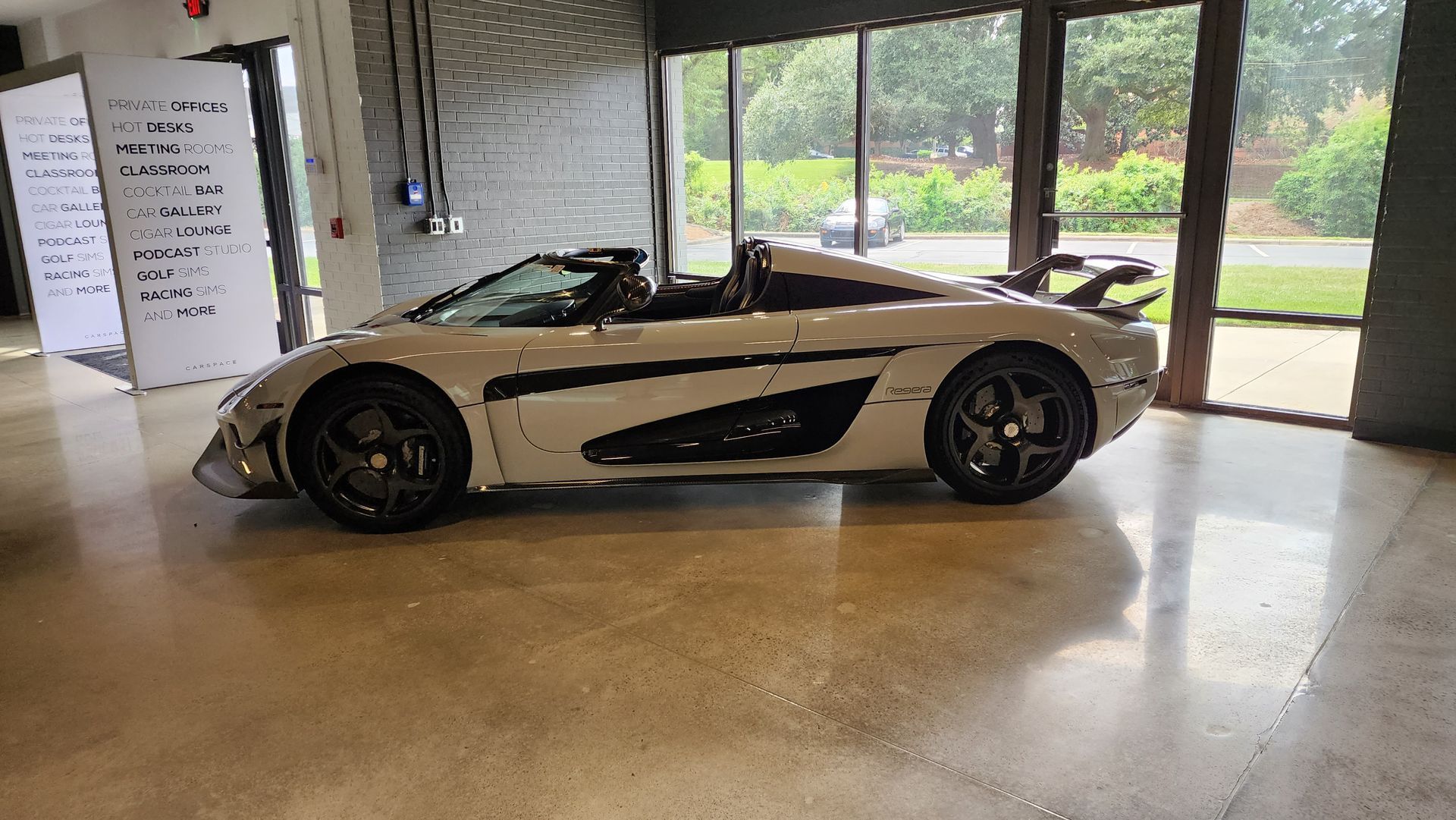 A white sports car is parked in a garage next to a window.