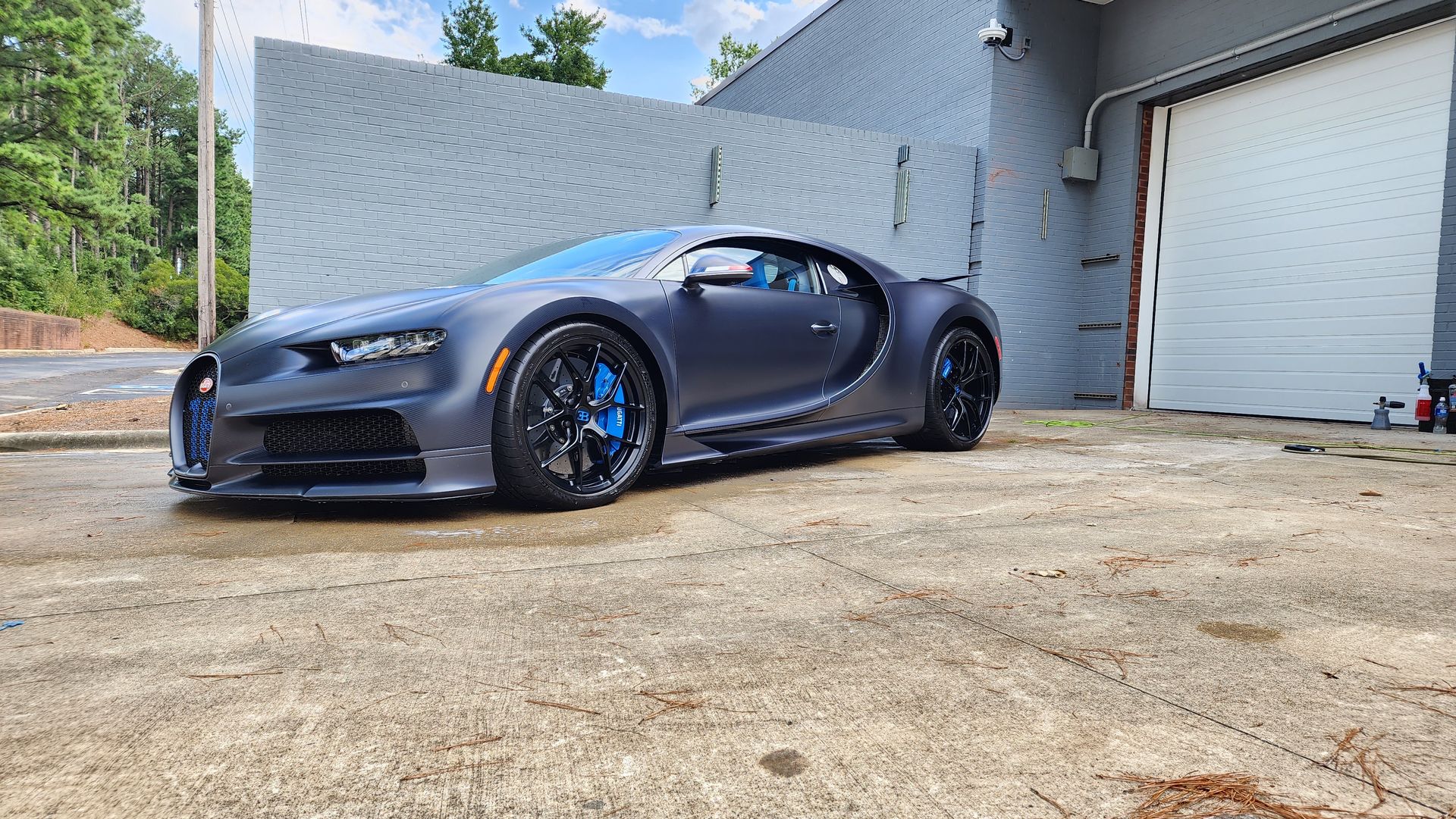 A gray sports car is parked in front of a garage.