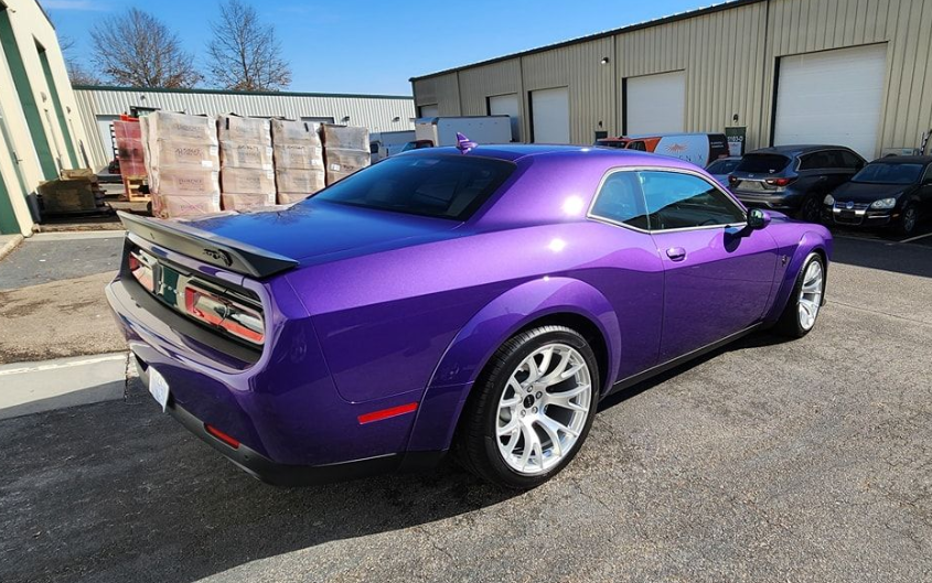 Purple Dodge Challenger sports car parked in front of a building.