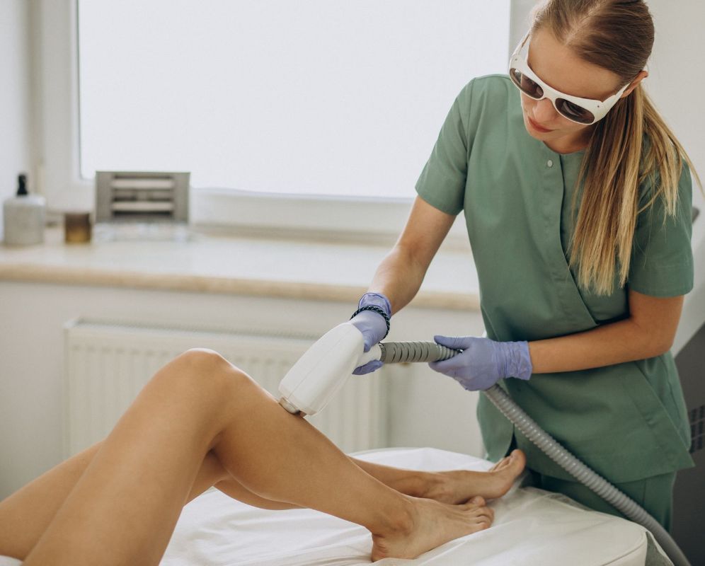 A woman is getting a laser hair removal treatment on her legs.