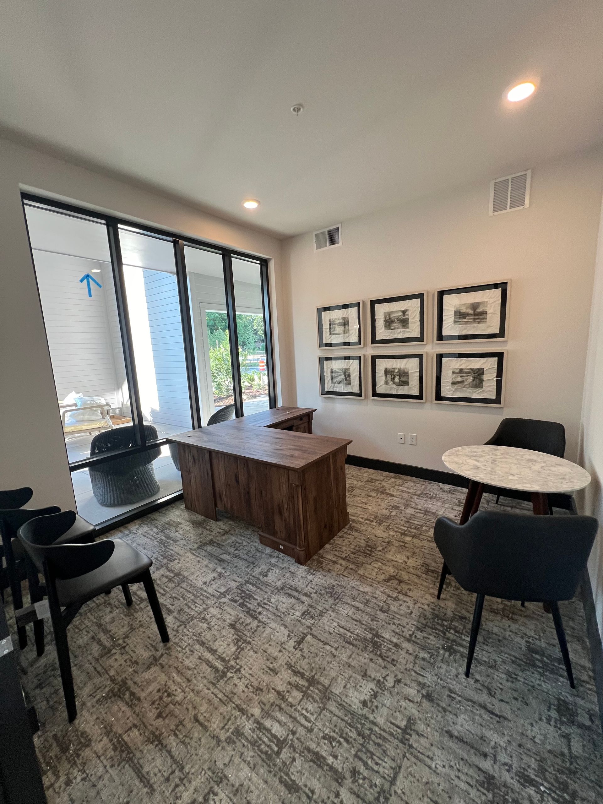A room with a desk , chairs , tables and pictures on the wall.