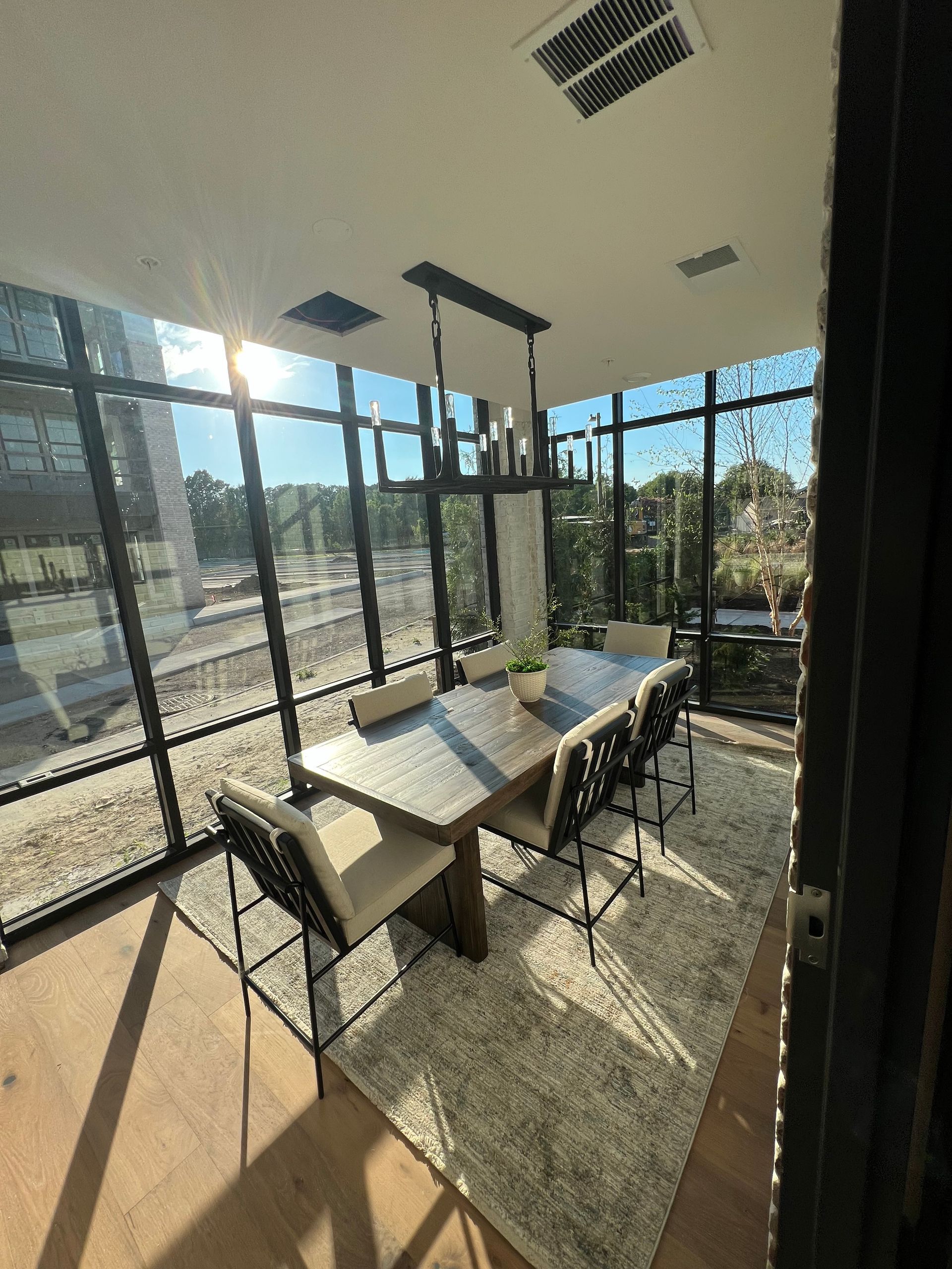 A dining room with a table and chairs and a lot of windows.