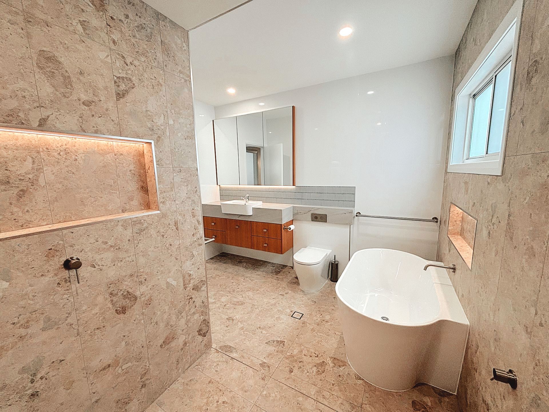  Home Electrical. A bathroom with a tub , toilet , sink and mirror. Down lights 