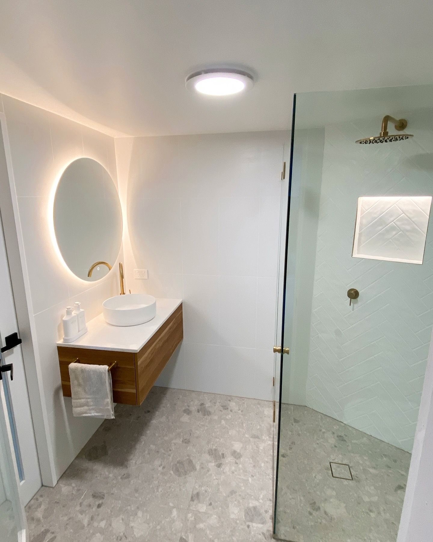 A bathroom with a sink , LED mirror , and walk in shower.